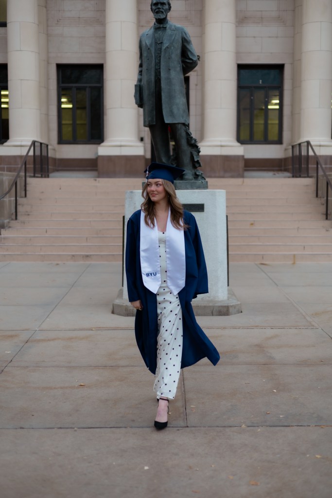 Lia walking in a Brigham Young University cap and gown.
